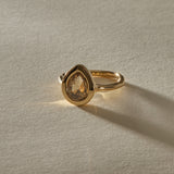 Aurum Pear Diamond Ring from the front, the champagne diamond glowing in warm light.