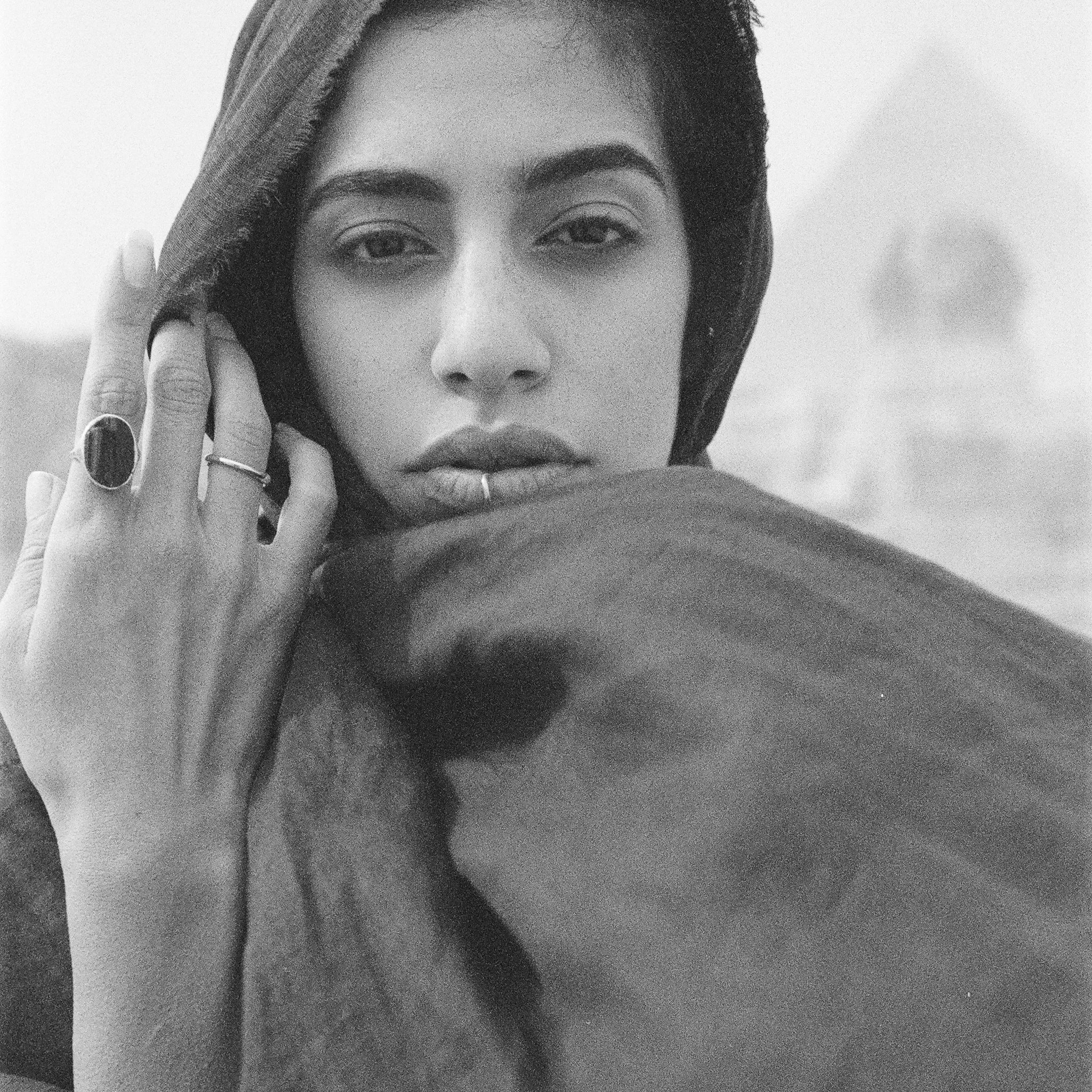 Model holding a scarf to her face, wearing a Black Tourmaline Amulet Ring in recycled gold.