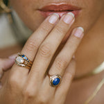 Model with her fingers to her lips, wearing the Cleo Lapis Lazuli Amulet Ring with stacked rings.