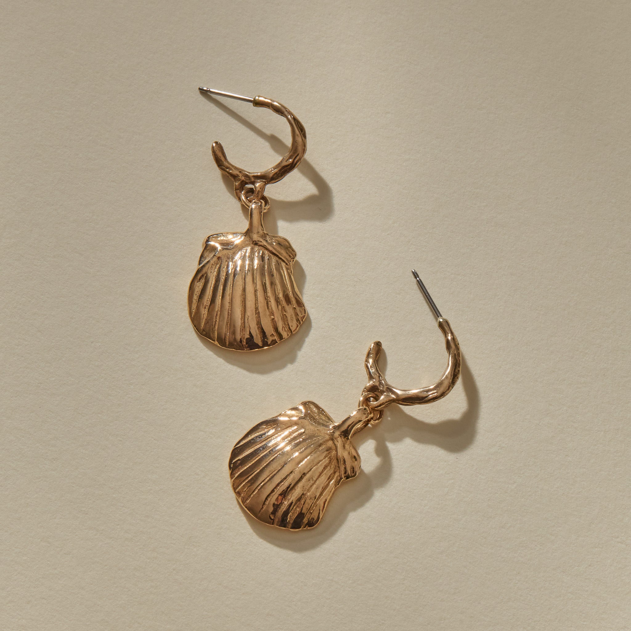 Elysian Shell Hoop Earrings in bronze laid flat, showing the ribbed scallop shells and slim hoops.