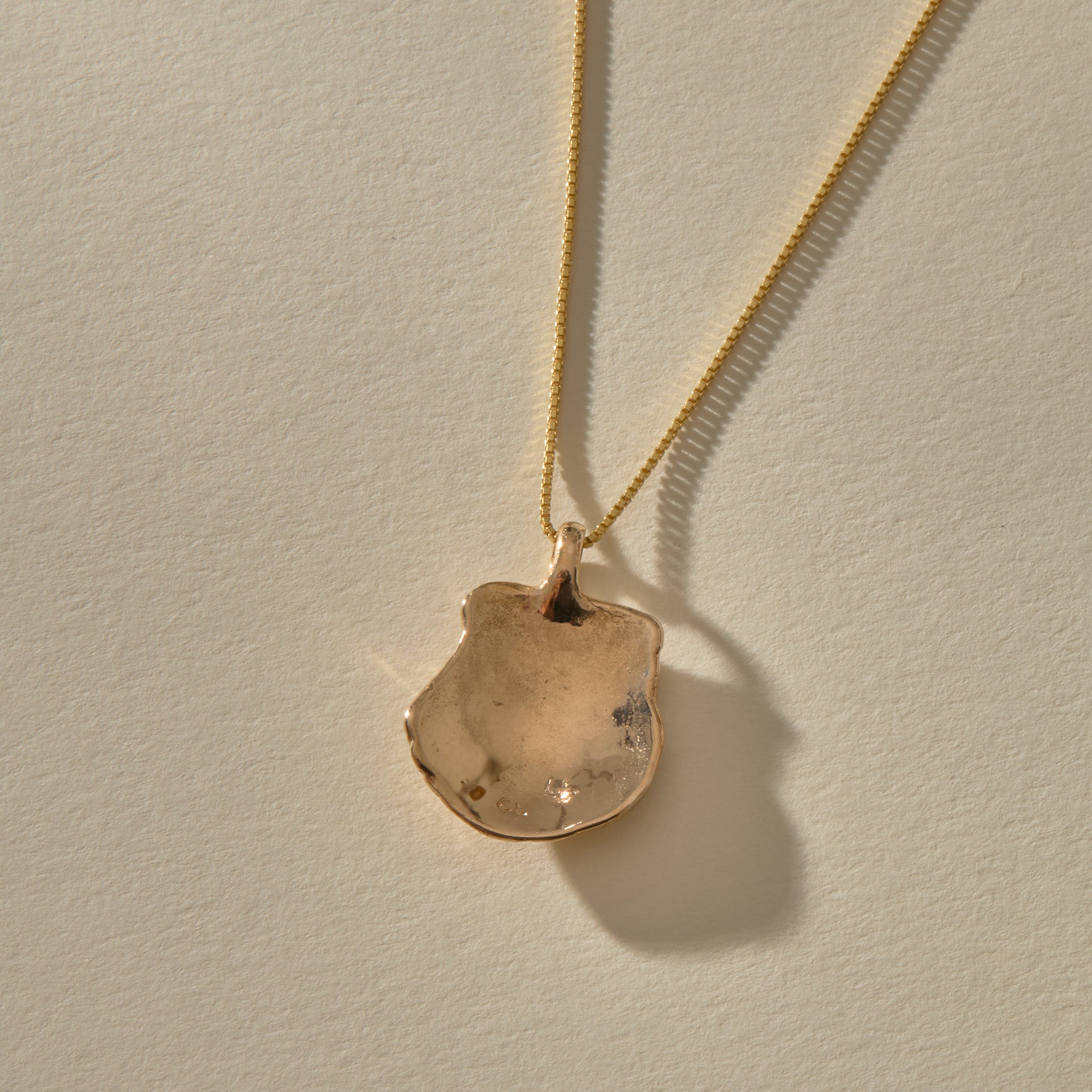 Back of the Elysian Shell Necklace pendant in bronze, showing the smooth inside of the shell.