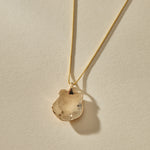 Back of the Elysian Shell Necklace pendant in gold, showing the smooth inside of the shell.