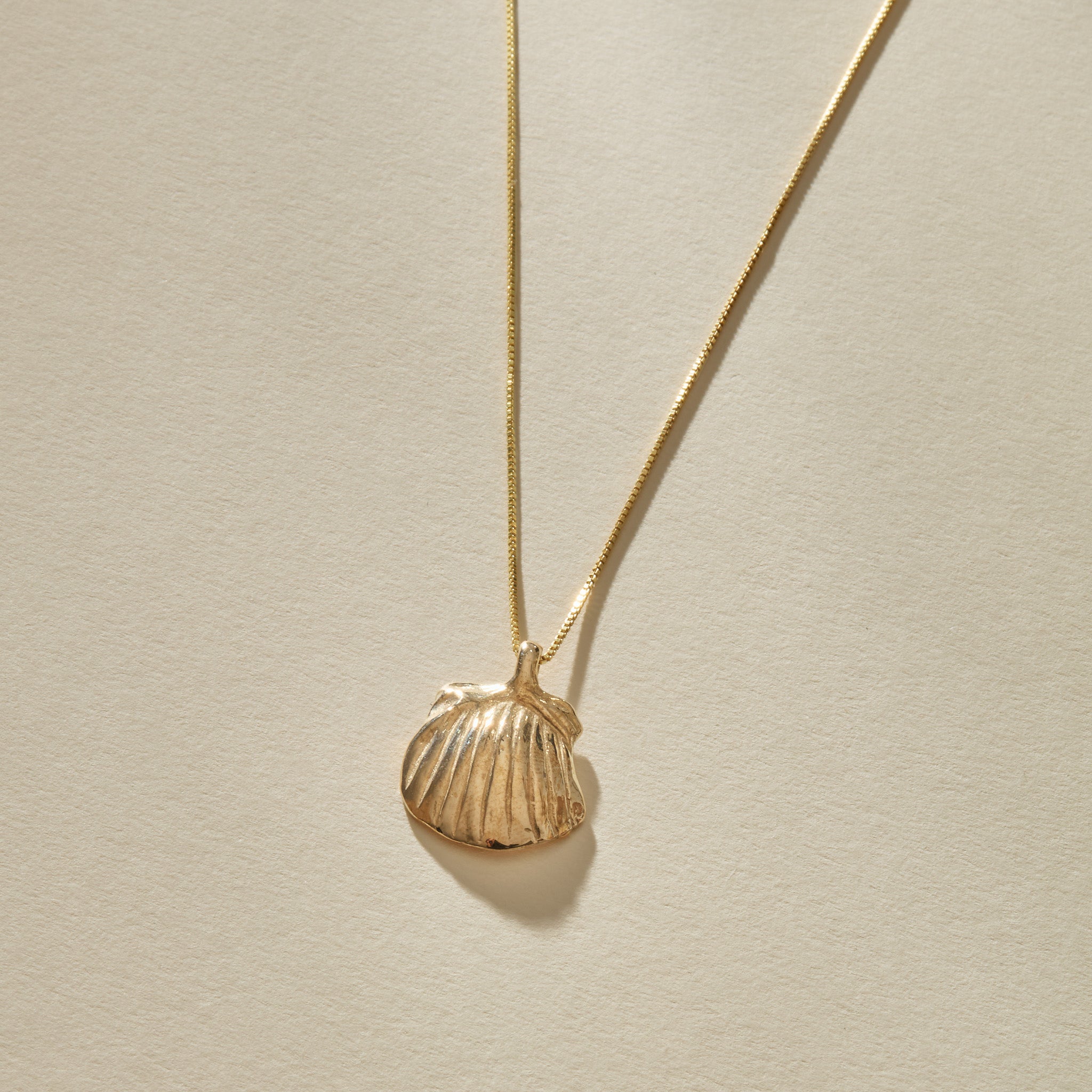 Elysian Shell Necklace in gold, a close view of the ribbed scallop shell pendant.