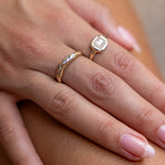Hands resting on a knee, wearing the Eros Five-Stone Champagne Diamond Band stacked with a pearl ring.