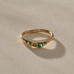 Eros Five-Stone Emerald Band in solid recycled gold at an angle, showing the graduated emeralds.