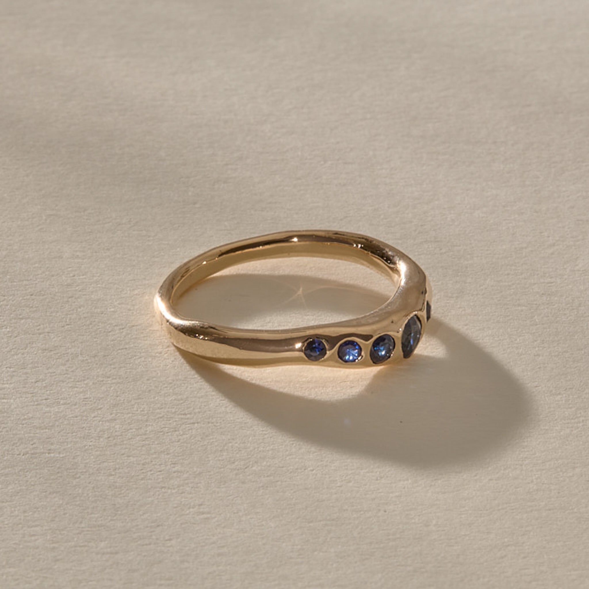 Eros Five-Stone Sapphire Band in solid recycled gold at an angle, showing the graduated blue sapphires.