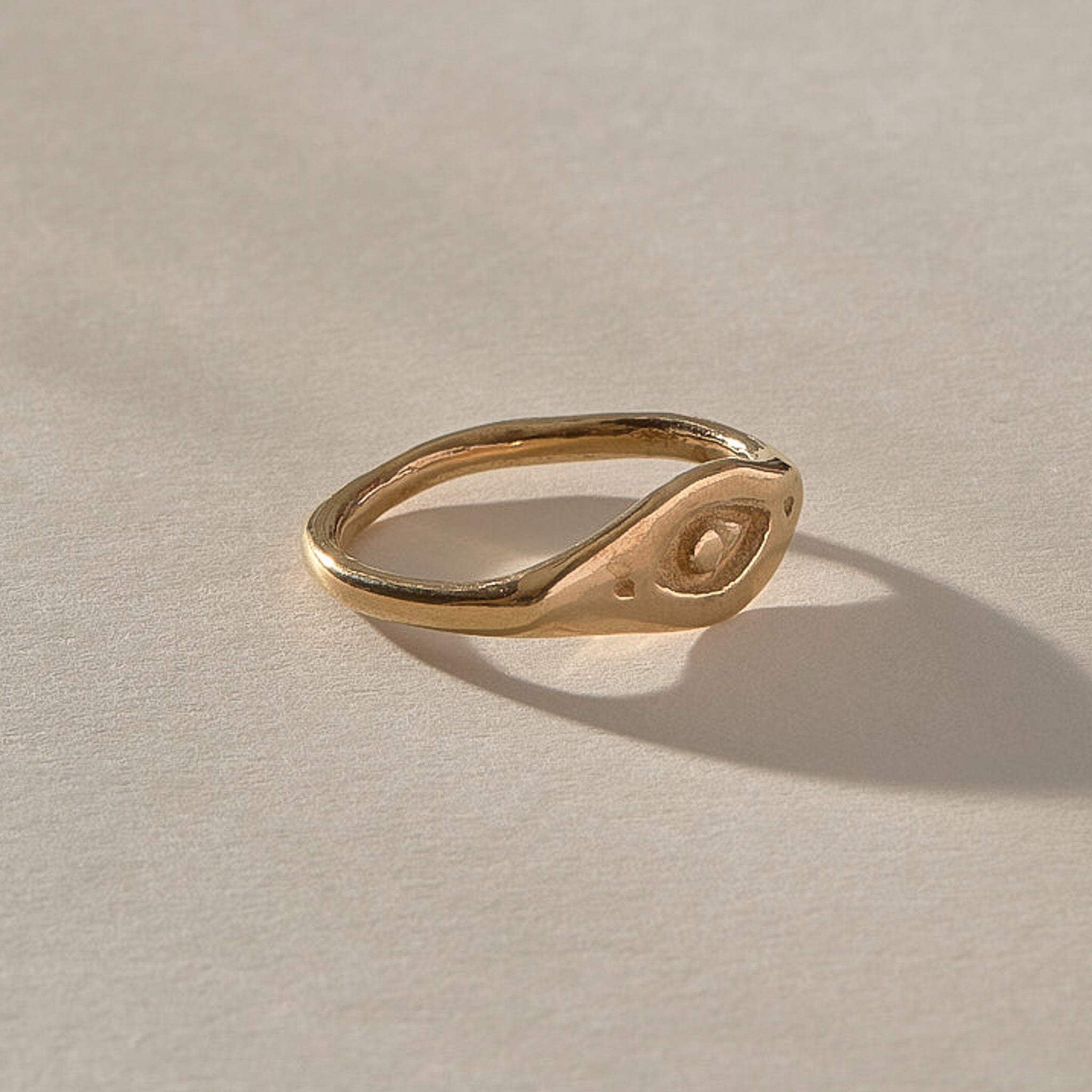 Evil Eye Protection Ring in solid recycled gold at an angle, showing the carved protective eye.