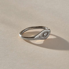 Evil Eye Protection Ring in recycled sterling silver at an angle, a carved protective eye set into an organic band.