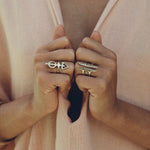 Hands holding a peach cardigan open, wearing the Ma'at Elemental Ring and Catori Life rings