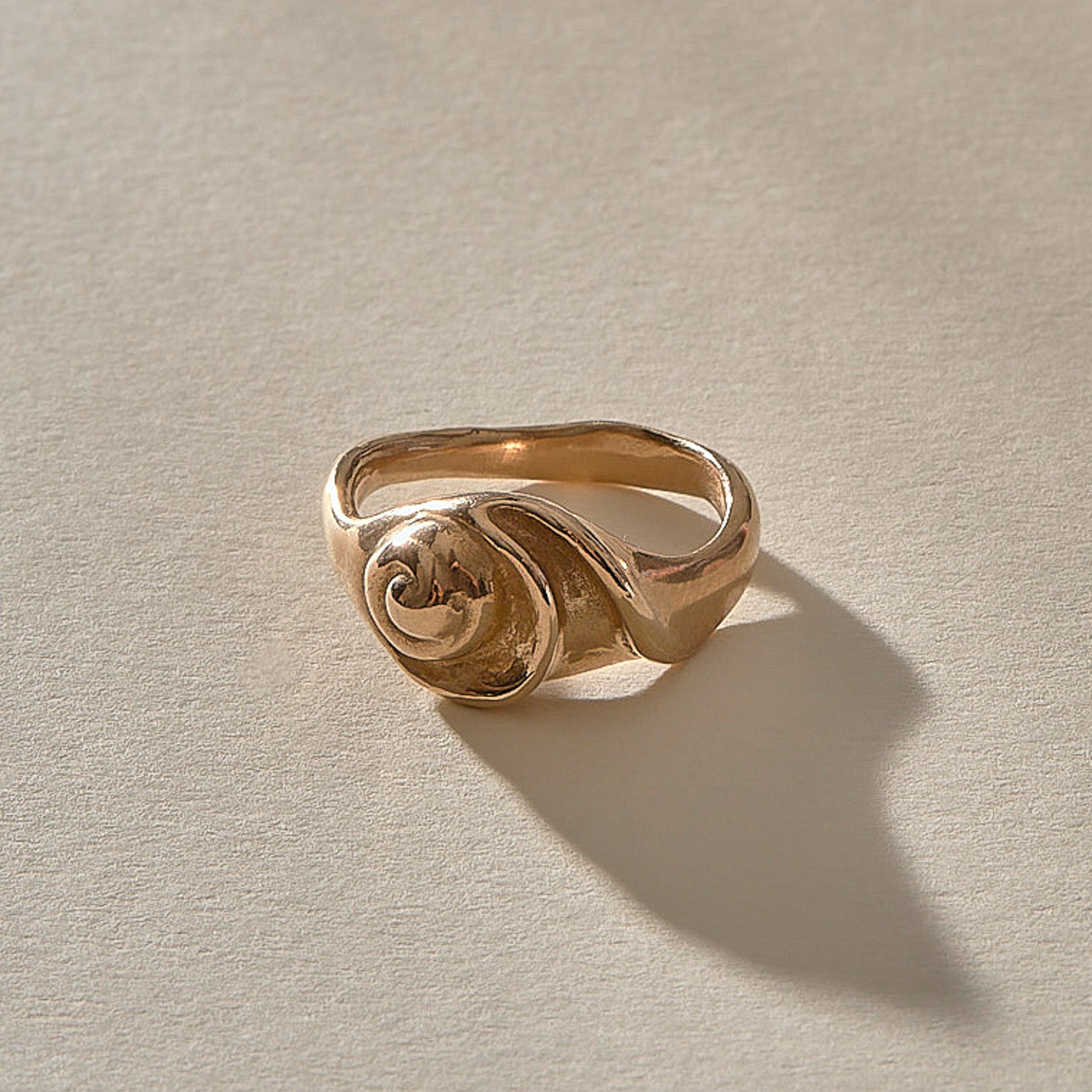 Neptune Spiral Shell Ring in recycled bronze, a hand-cast spiral seashell set on a wavy organic band.