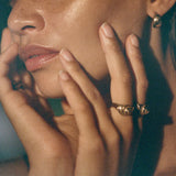 Neptune Spiral Shell Ring worn on the hand, fingers resting at the model's cheek.