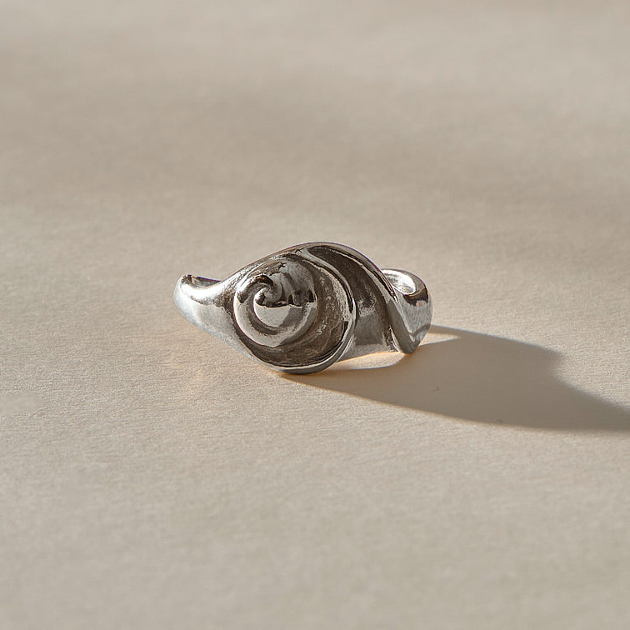 Neptune Spiral Shell Ring in sterling silver from a low angle, the spiral shell rising from the band.