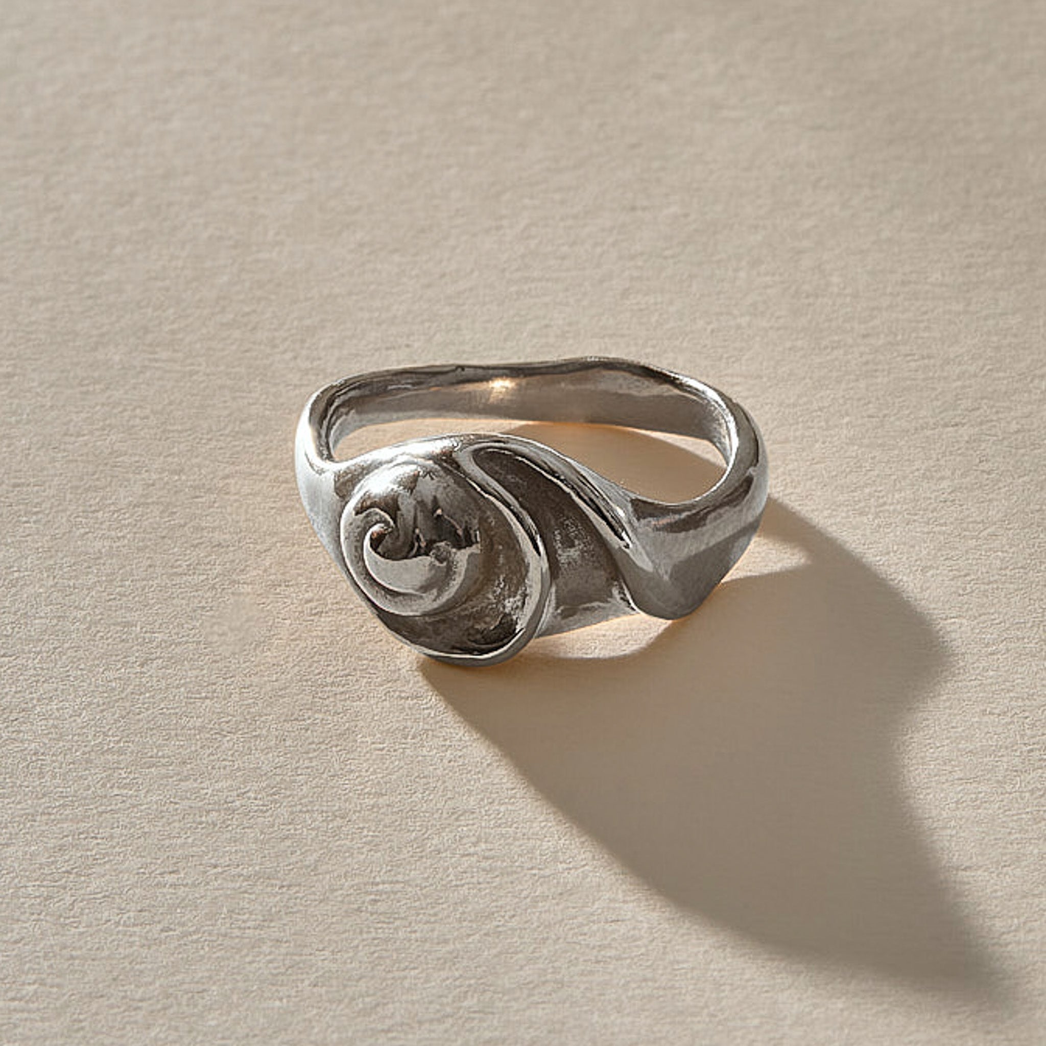 Neptune Spiral Shell Ring in recycled sterling silver, a hand-cast spiral seashell set on a wavy organic band.