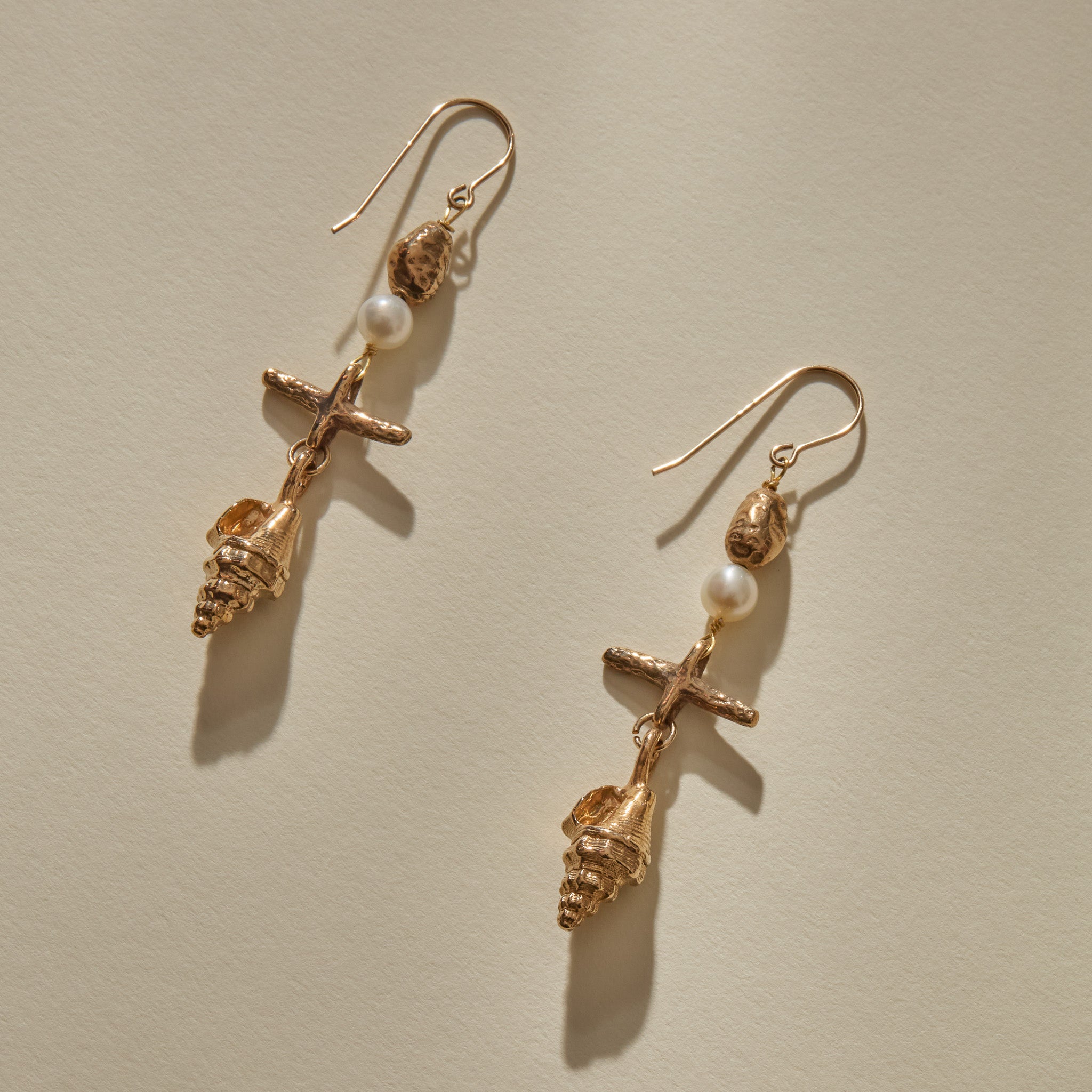 Sereia Shell and Pearl Chandelier Earrings in bronze laid side by side, showing each tier of the drop.