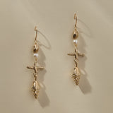 Sereia Shell and Pearl Chandelier Earrings in gold hanging side by side, showing each tier of the drop.