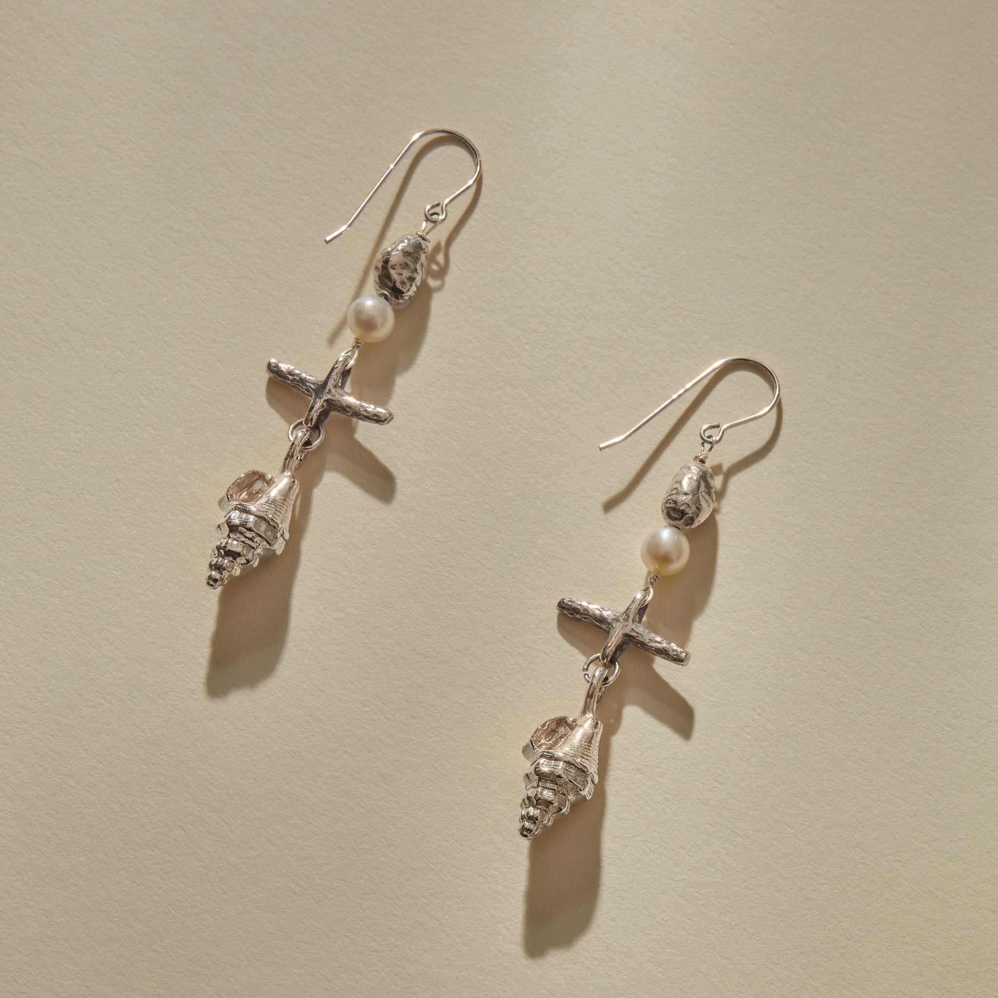 Sereia Shell and Pearl Chandelier Earrings in sterling silver laid side by side, showing each tier of the drop.