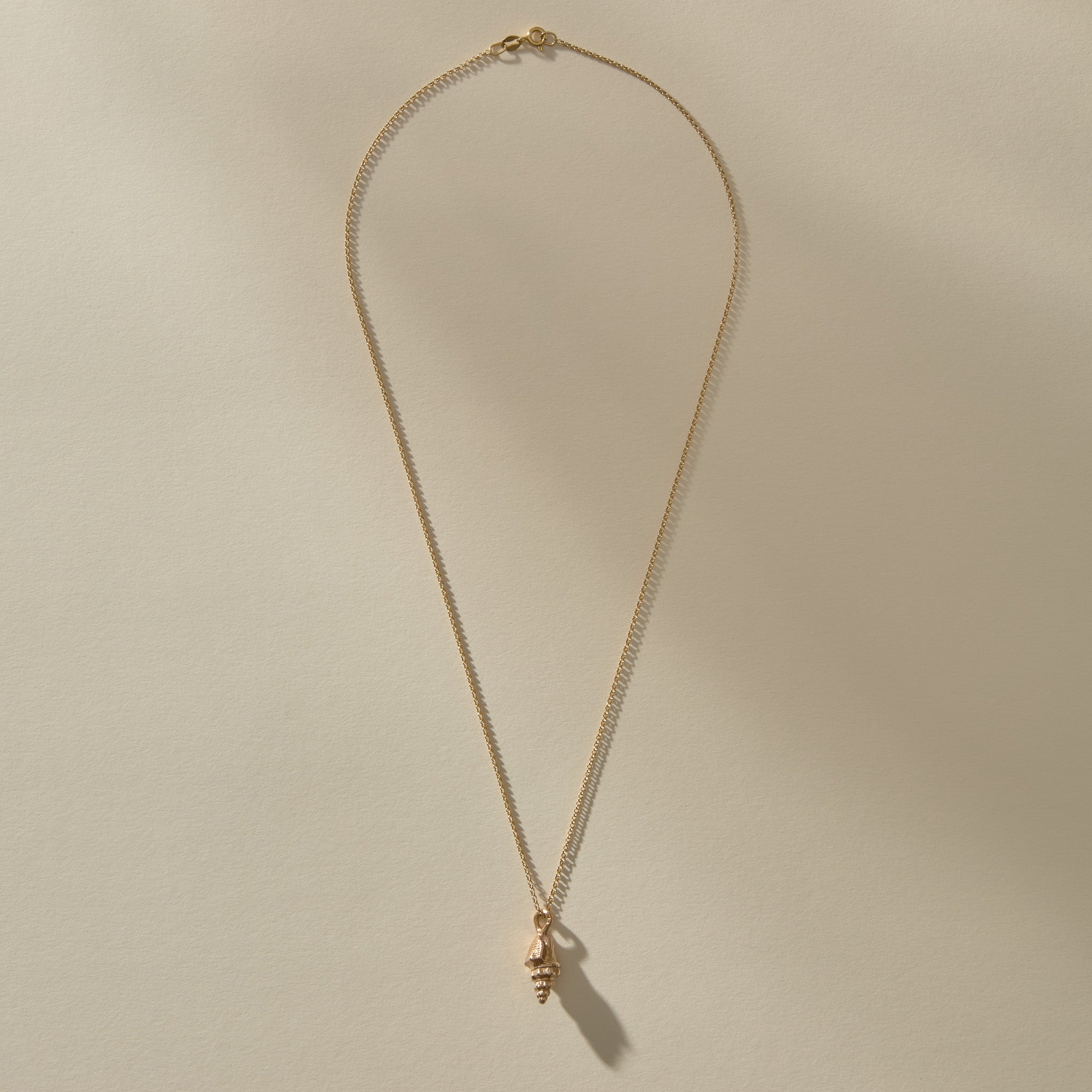 Full length of the Sereia Spiral Shell Necklace in bronze on its 20 inch chain.