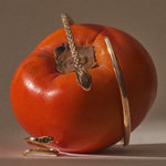 Serpent Snake Arm Cuff in solid recycled gold wrapped around a persimmon, beside a serpent ring.
