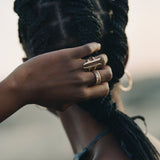 Model gathering her braids, wearing the Akash Shield Statement Ring with stacked rings.
