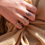 Hand gathering golden fabric wearing the Evil Eye Protection Ring stacked with other rings.