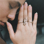 Model with hands in prayer near her face, wearing the Ma'at Elemental Ring stacked with Catori Life rings