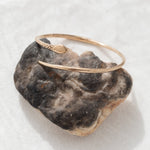 Serpent Snake Arm Cuff resting on a dark stone, showing the carved snake head.