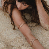 Serpent Snake Arm Cuff worn on the arm of a model lying in the sand.